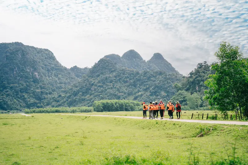 Đoàn khách đi bộ qua thung lũng vào hang